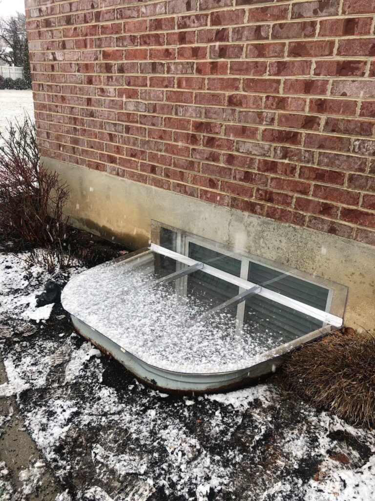 A snow-covered window on the side of a building showcasing a winter scene