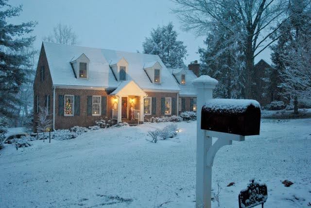 A cozy house with snow on the ground and a mailbox, creating a serene winter scene