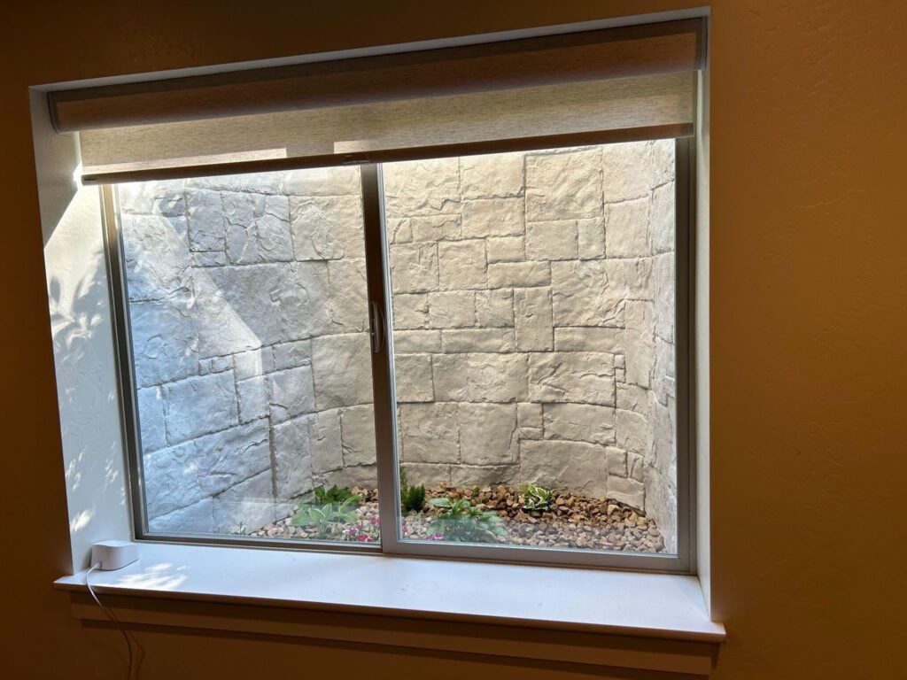 A stone wall surrounds a windo with a green plant placed on the sill adding a touch of nature to the scene