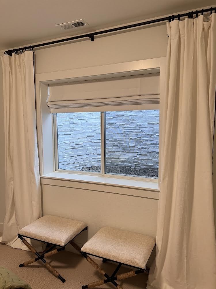 A bright window with flowing white curtains and a comfortable bench below