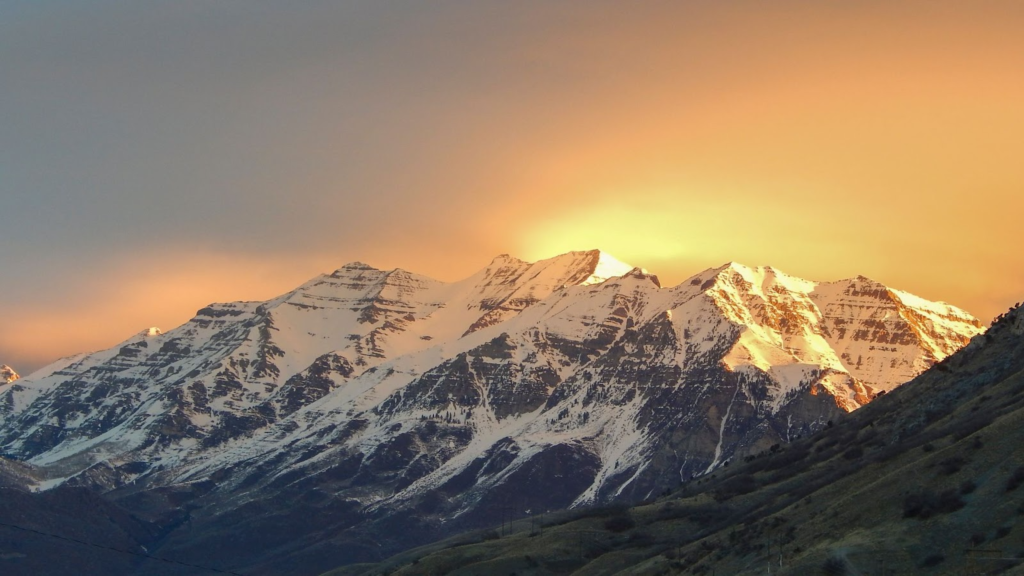 A breathtaking sunset illuminates snow-capped peaks of a majestic mountain range.