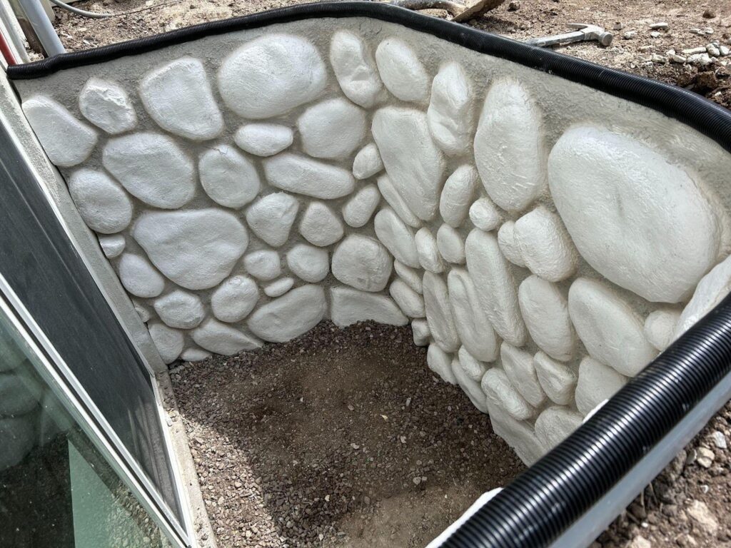 A sturdy concrete wall featuring rocks, creating a unique texture and design