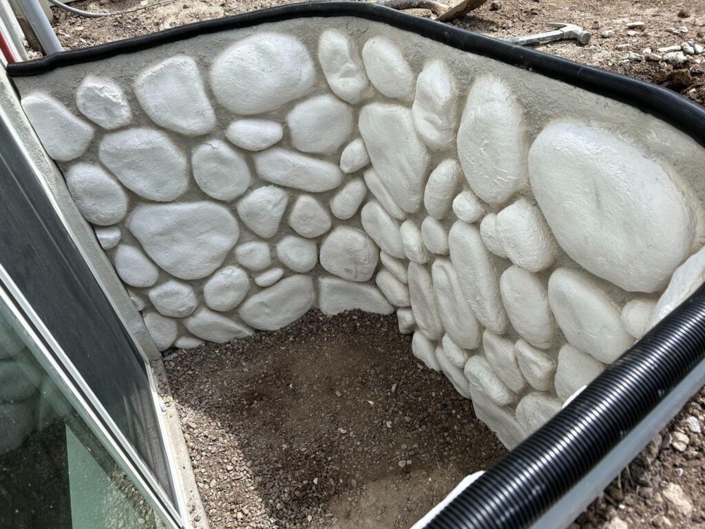 A concrete wall embedded with various sized rocks showing a rugged and textured surface